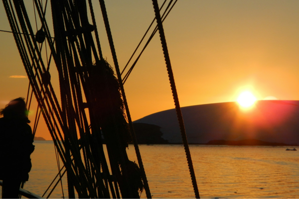 Person looking towards sunset through a sailing ship's rigging