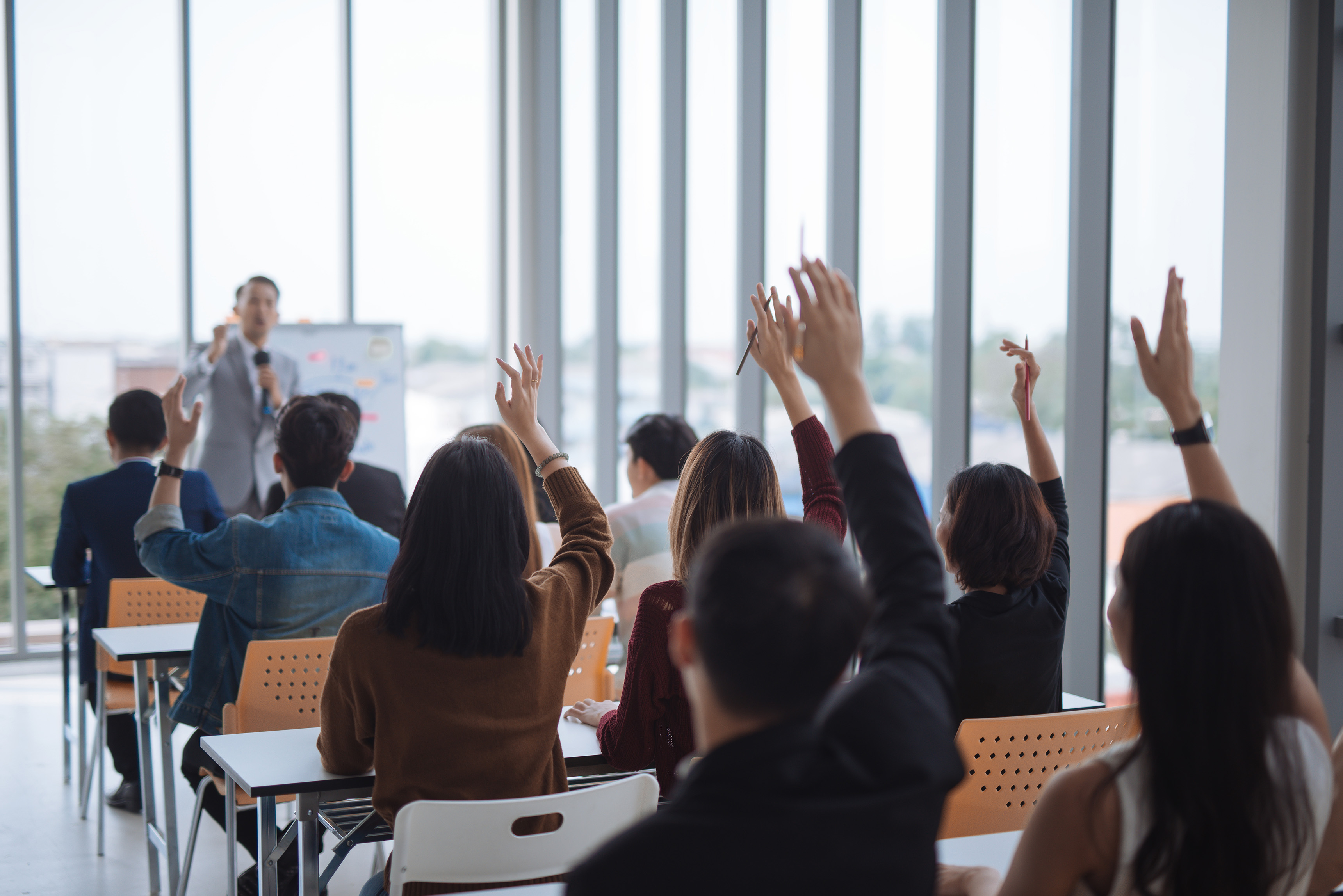people in a classroom with their hands raised