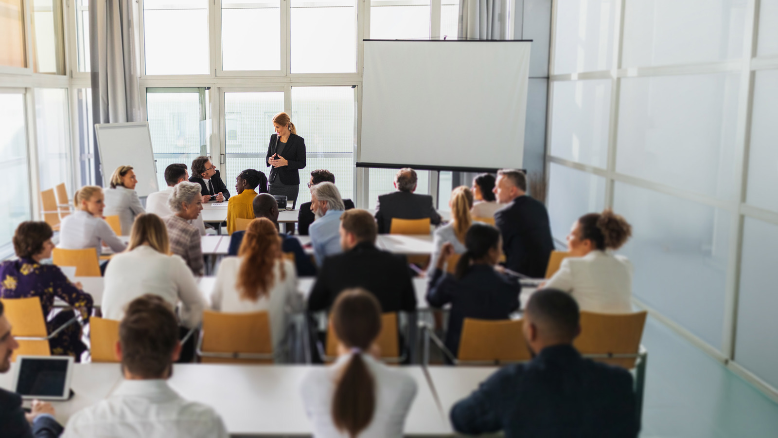 People in a classroom with a trainer talking to them and a whiteboard