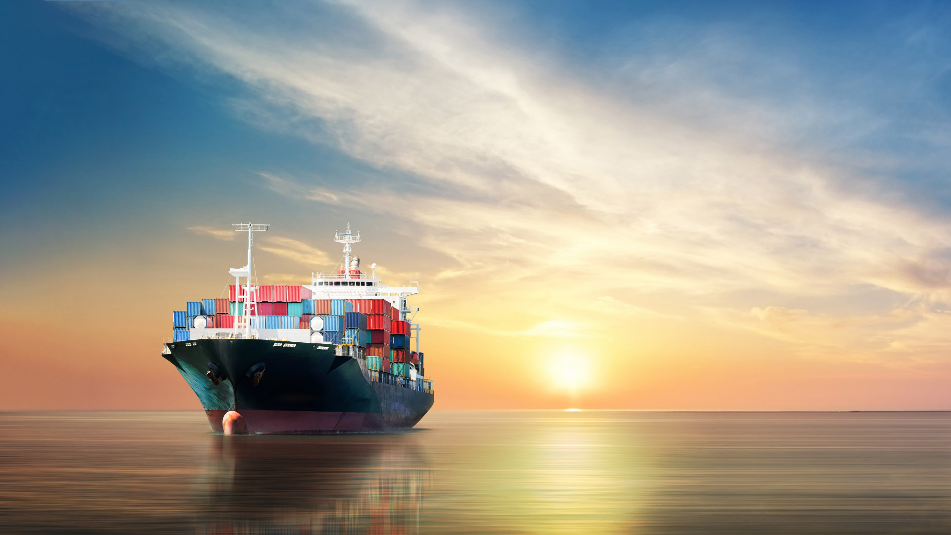 Container ship on the sea with a sunrise/sunset on the horizon