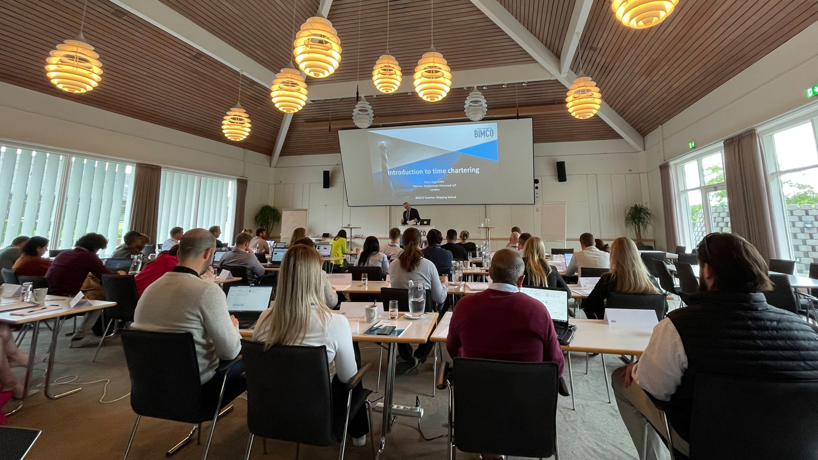people in a conference room with a speaker at the front on a podium