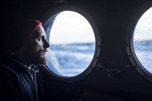A seafarer looking out of a ship's porthole