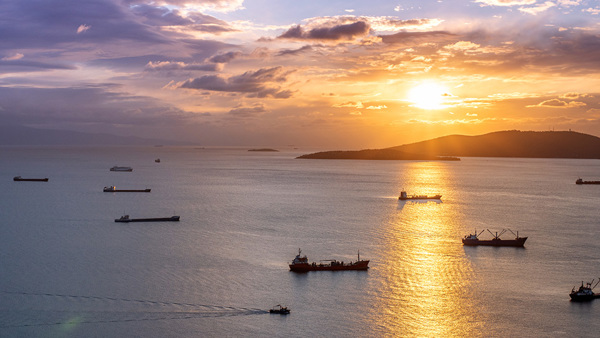 Multiple ships at sea with a sunset
