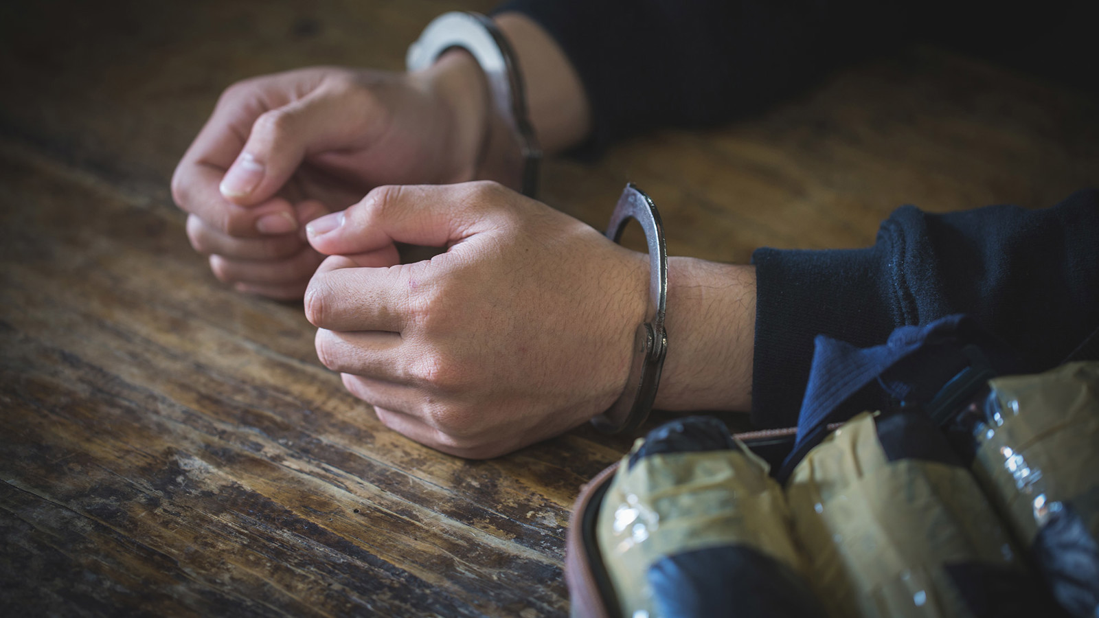 Hands in handcuffs alongside smuggled drug packets